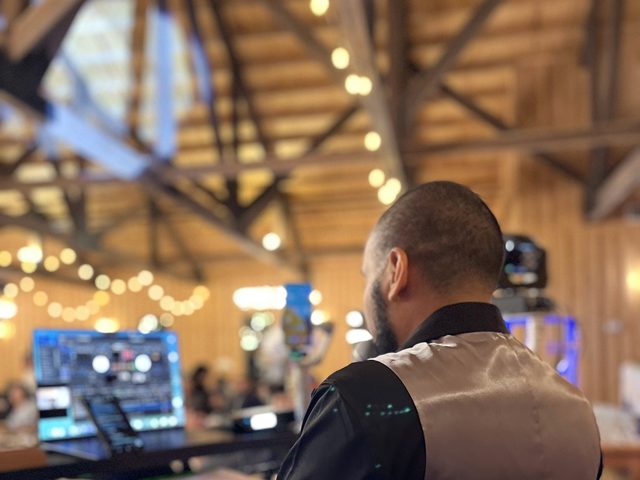 DJ booth set for a barn wedding reception, string lights overhead