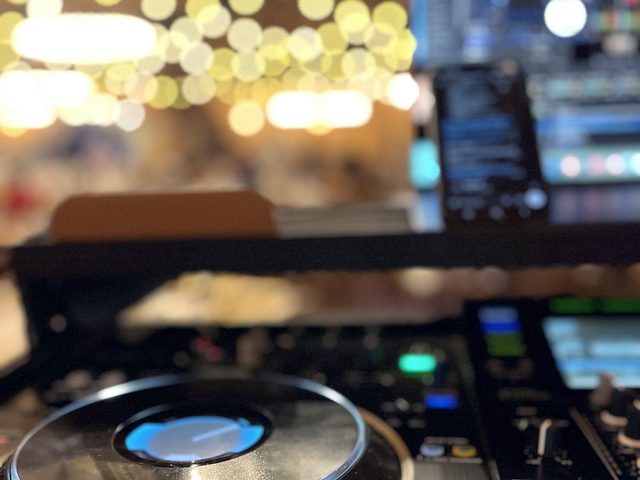 Close view of the DJ controller with venue string lights behind it