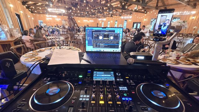 View from the DJ booth across a full barn wedding reception