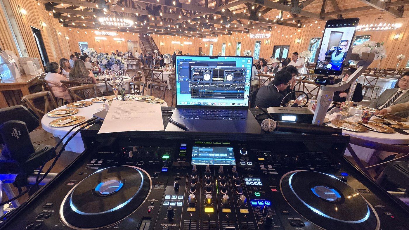 View from the DJ booth across a full barn wedding reception